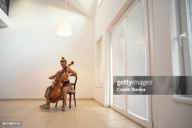 young woman playing violoncello at home - cellist stock pictures, royalty-free photos & images