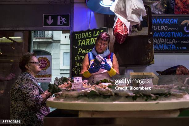 Fishmonger uses a card payment machine to process a customer's payment for fresh fish in the Sant Antoni market in Barcelona, Spain, on Wednesday,...