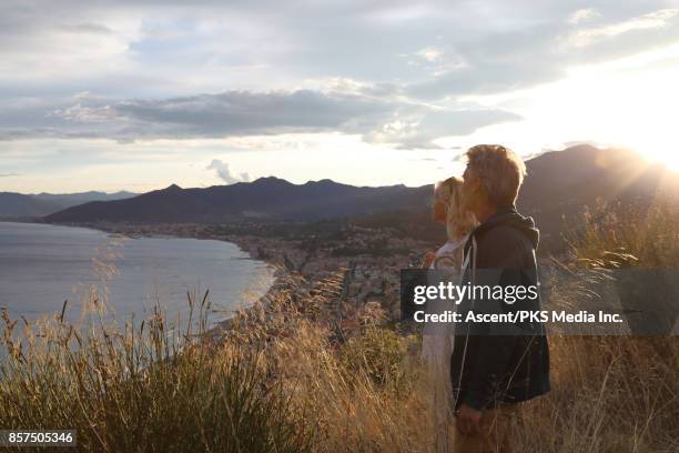 mature couple pause on mountain slope above sea, village - mature woman in sun foto e immagini stock