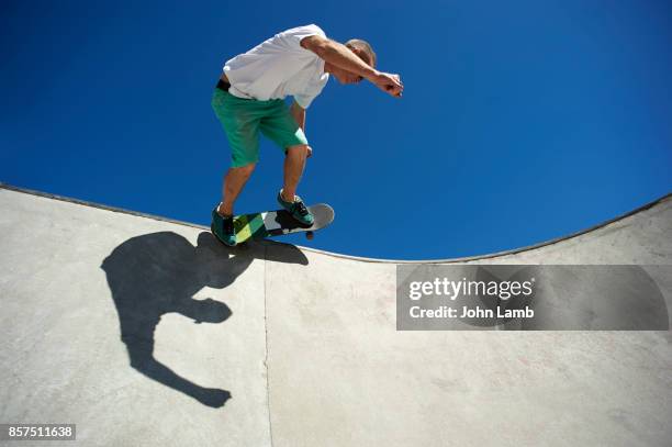 skateboarder at edge of skateboard park bowl. - skateboard foto e immagini stock