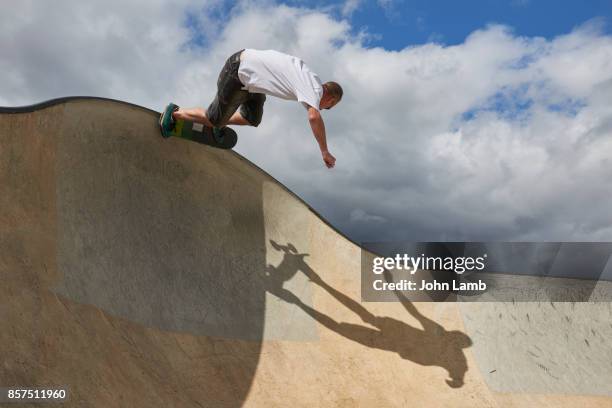 skateboarder at edge of skateboard park bowl. - paparazzi stock pictures, royalty-free photos & images