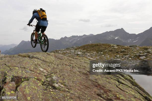 mountain biker pops wheelie on high mountain ridge - wheelie stock pictures, royalty-free photos & images