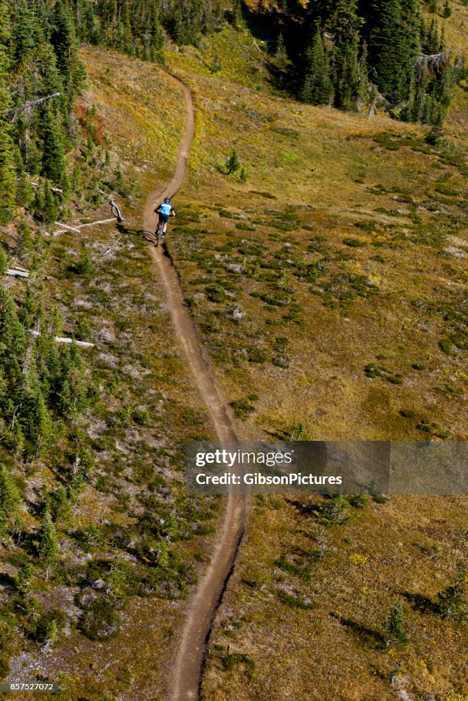 An aerial view of a man riding a mountain bike trail in British Columbia, Canada.