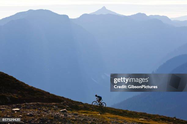 een man rijdt op een steile berg-fietsweg in brits-columbia, canada. - mountainbiken stockfoto's en -beelden