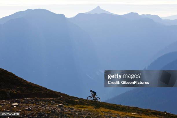um homem monta uma trilha de bicicleta de montanha íngreme na colúmbia britânica, canadá. - íngreme - fotografias e filmes do acervo