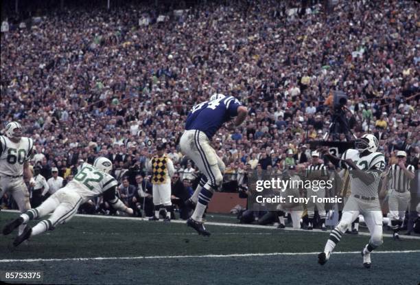 Defensive back Randy Beverly of the New York Jets looks up at the ball after it bounced off the pads of tight end Tom Mitchell of the Baltimore Colts...