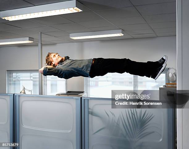 man sleeping floating above his office table. - levitación fotografías e imágenes de stock