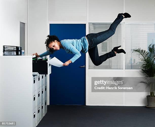 woman working in  an office floating above the flo - levitación fotografías e imágenes de stock