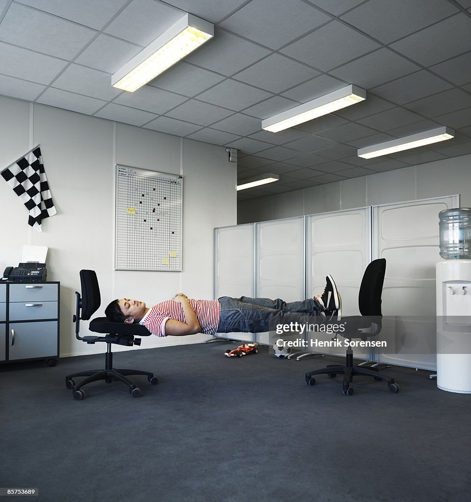 Man sleeping in his office on two chairs.