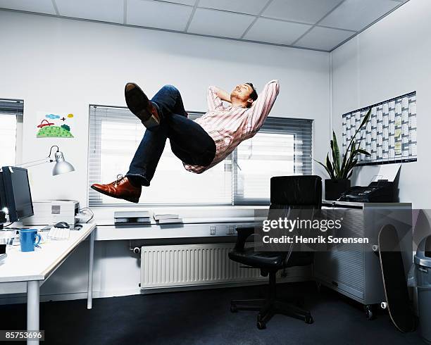 man floating in his office. - hands behind head - fotografias e filmes do acervo