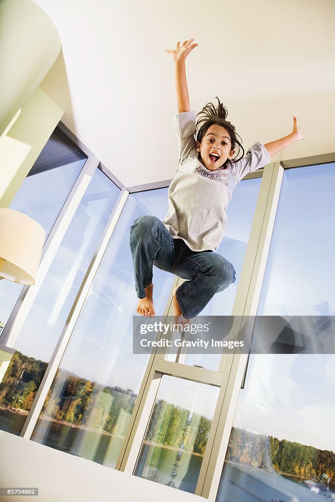 Teenage girl jumping high on sofa bed