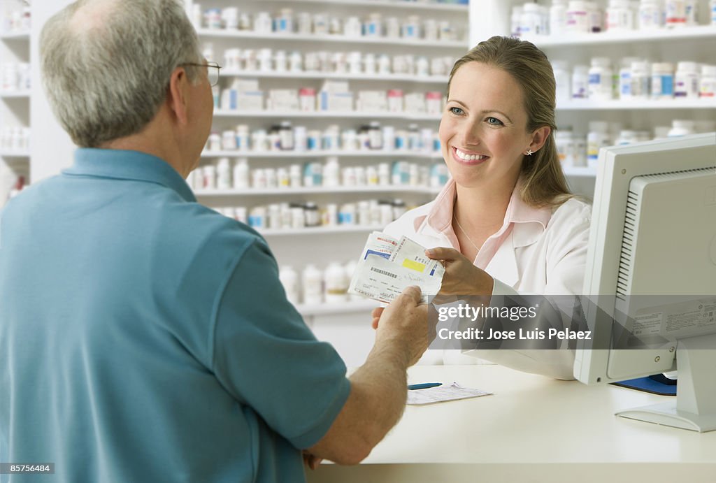 Pharmacist handing man prescription