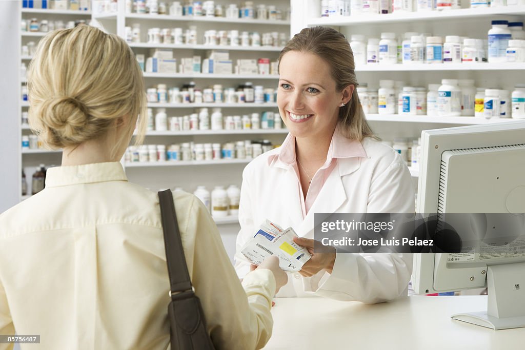 Pharmacist handing woman medication