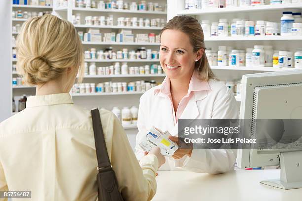 pharmacist handing woman medication - pharmacy imagens e fotografias de stock