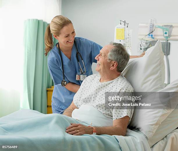 female nurse with male patient - adult male hospital bed stock-fotos und bilder