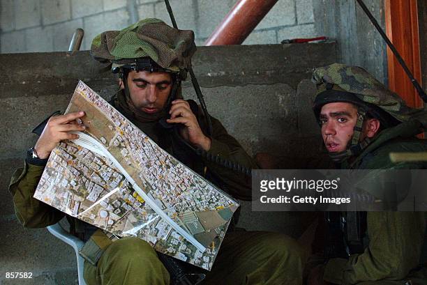 Israeli officers study a map inside a Palestinian house in the Tulkarem refugee camp in the West Bank March 7, 2002 as Israeli troops, backed by...