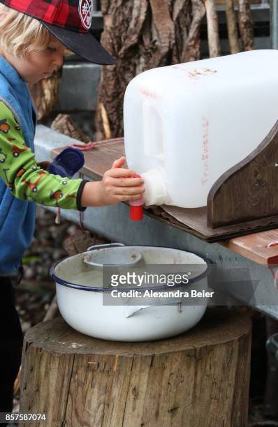 Boy fills water in a washbowl to wash his hands in a forest kindergarten on July 31, 2017 in Wessling, Bavaria, Germany. The forest kindergarten is a...