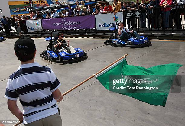 Driver Denny Hamlin and Dallas Cowboys tight end Jason Whitten prepare to take the green start flag while racing around the track at SpeedZone April...