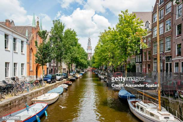 church and boats moored along the canal in amsterdam, holland - estrecho fotografías e imágenes de stock