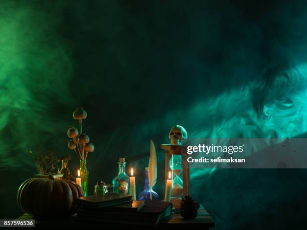 pumpkin, poison bottle, dead insects, candles, human skull and magic book for halloween - green potion stock pictures, royalty-free photos & images