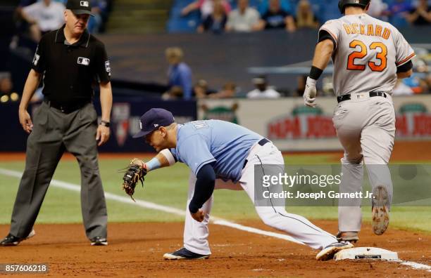 Logan Morrison of the Tampa Bay Rays holds onto the ball for the out at first as Joey Rickard of the Baltimore Orioles crosses first base during...