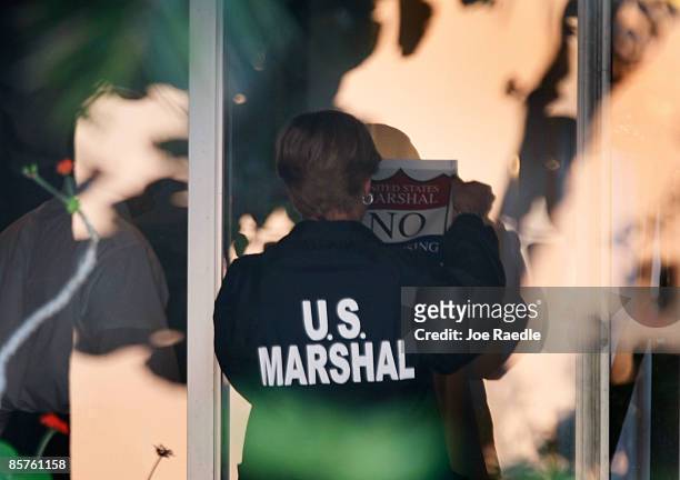 Marshal puts up a "United States Marshal No Trespassing" sign on a sliding glass door on the back porch of the house of imprisoned financier Bernard...