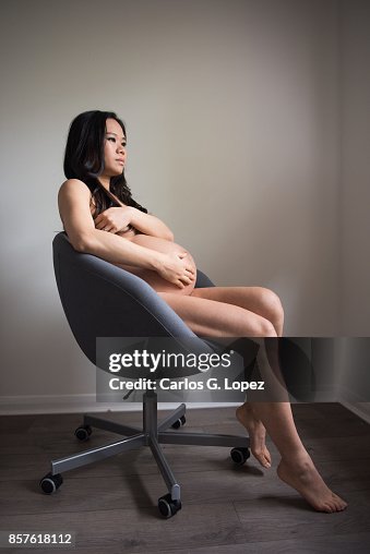 Pregnant Asian Woman Sits On Office Chair Exposing Her Changing