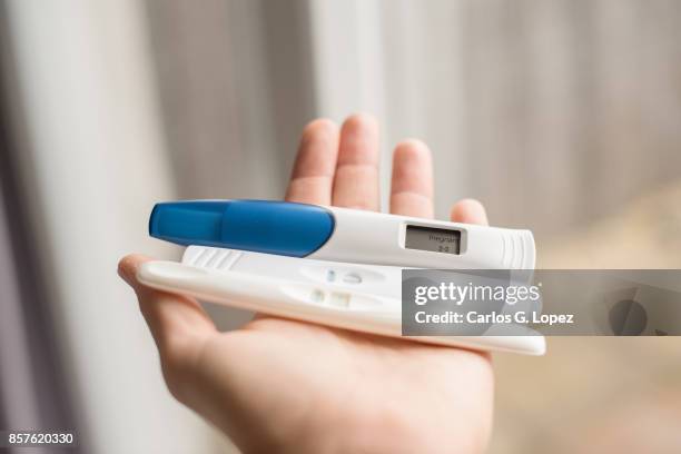 man's hand holding a pregnancy test revealing the positive outcome  - pregnancy/birthpregnancy/birth - pregnancy test stock pictures, royalty-free photos & images