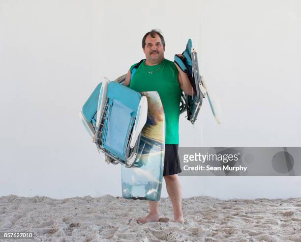 man with mustache holding beach chairs and boogie boards - destin beach stock-fotos und bilder