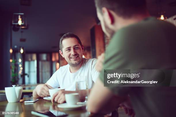 due amici sorridenti che bevono caffè e socializzano in un caffè - coffee meeting with friends foto e immagini stock
