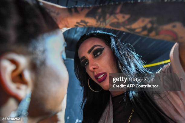 Transgender musician MC Trans puts make-up on one of her dancers backstage before their performance at the Emocoes nightclub in the Rocinha favela or...