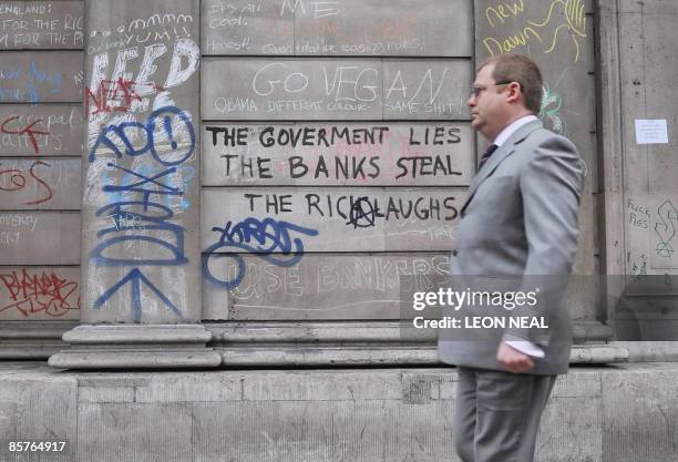 City worker walks past graffiti on the walls of the Bank of England in central London, on April 2, 2009. Angry protestors clashed with riot police...
