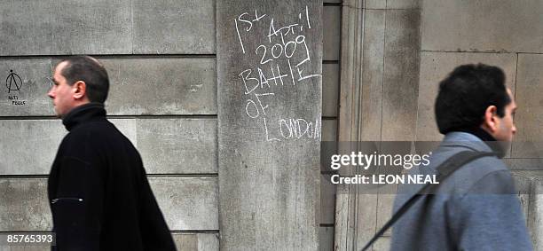 City workers walk past grafitti left by protestors on a wall of the Bank of England in central London, on April 2, 2009. Angry protestors clashed...