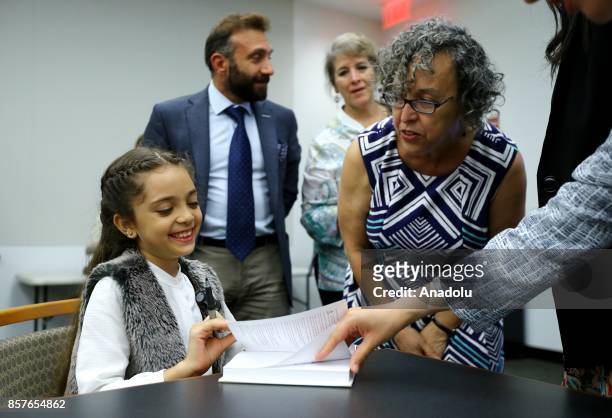 Bana Alabed , the 8-year-old Syrian girl who fled to Turkey from the war-torn Syrian city of Aleppo, signs her book named; 'Dear World: A Syrian...