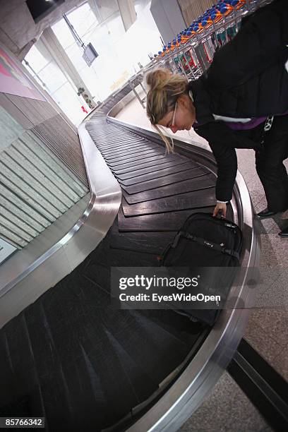 Woman picks up her suitcase from the luggage belt at the famous france CDG Charles de Gaulle airport in Paris, FEBRUARY 25, 2009.