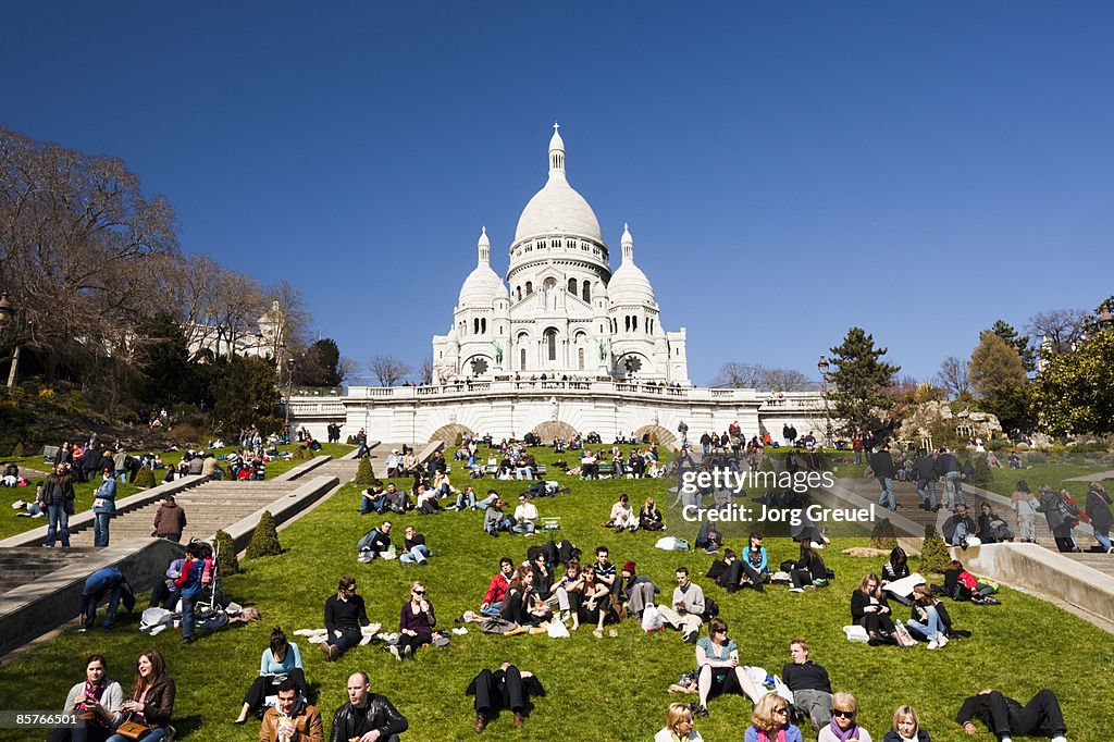 People lying on lawn in front of Sacre Coeur