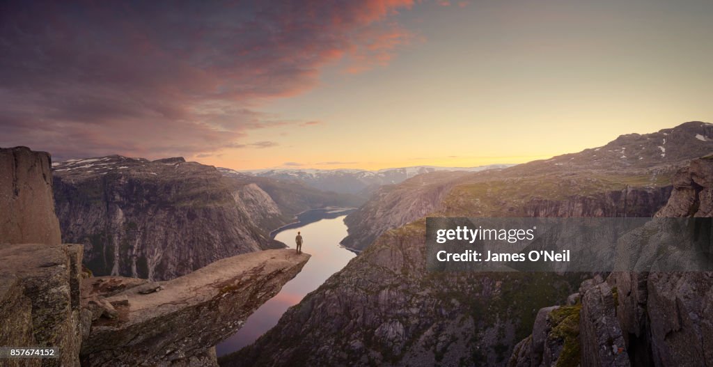 Panoramic of traveller looking out at landscape at sunset, Trolltunga, Norway