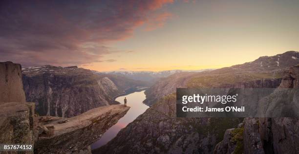 panoramic of traveller looking out at landscape at sunset, trolltunga, norway - imponente fotografías e imágenes de stock