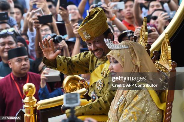 Brunei's Sultan Hassanal Bolkiah and Queen Saleha wave from the royal chariot during a procession to mark his golden jubilee of accession to the...