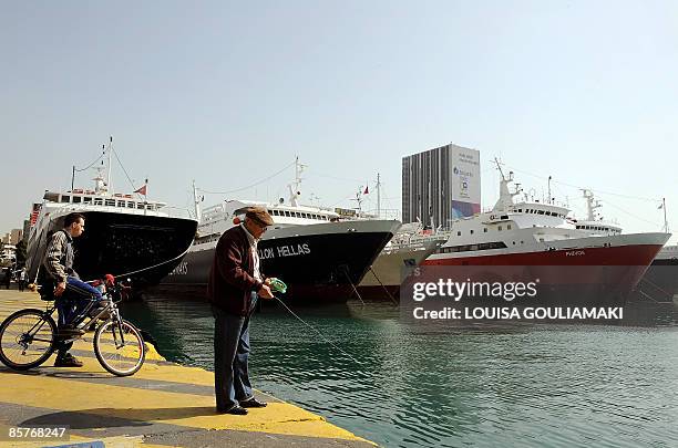 Man fishes in the water by ferry-boats in the dock at the port of Piraeus near Athens on April 2, 2009 during a 24-hour strike staged to protest...