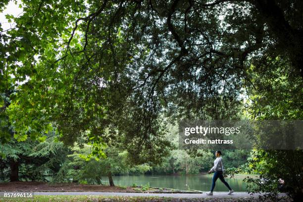 una mujer afroamericana toma un paseo en el parque público - battersea park fotografías e imágenes de stock