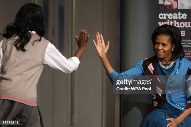 First Lady Michelle Obama raises her arm to touch hands with a student during a visit to the Elizabeth Garrett Anderson Secondary School on April 2,...