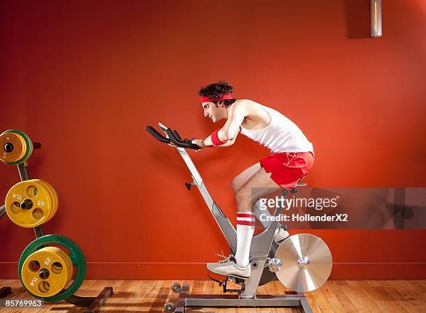 man on exercise bike with headband and kneesocks - adult male vest exercise stock pictures, royalty-free photos & images