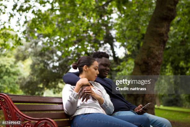 young african american couple sitting on the park bench - battersea park stock pictures, royalty-free photos & images