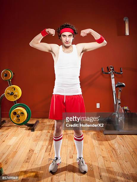 skinny man making muscles at gym - indecisive stock-fotos und bilder