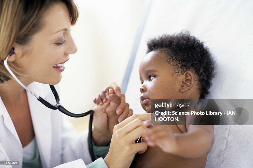 Doctor listening to baby boy's (2-5 months) chest sounds, using stethoscope