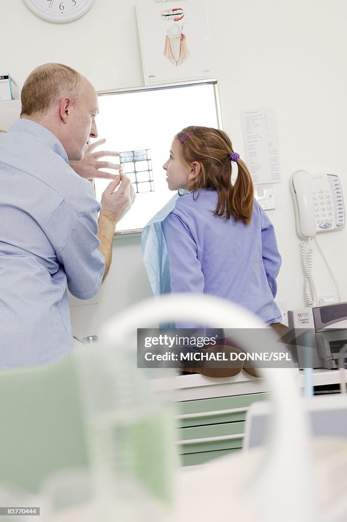 Girl (8-9) having her dental X-ray explained to her by dentist