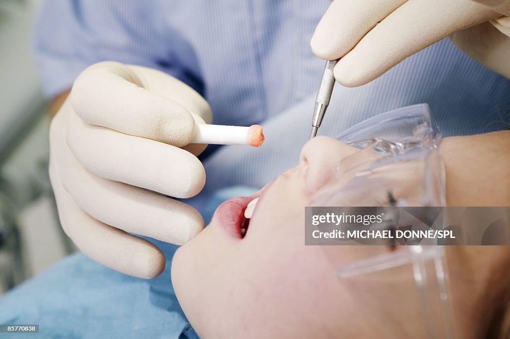 Dentist performing dental treatment on young girl (8-9)