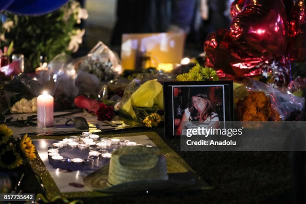 People light candles, place figures and flowers at a makeshift memorial set up along the Las Vegas Strip for the Las Vegas mass shooting victims, who...