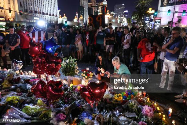 People light candles, place figures and flowers at a makeshift memorial set up along the Las Vegas Strip for the Las Vegas mass shooting victims, who...